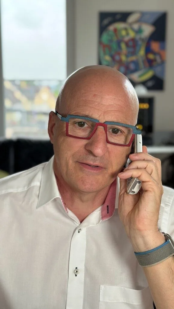 Man in glasses on phone call indoors.