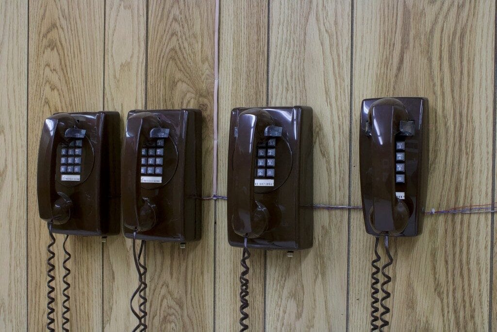 Vier braune Wandtelefone auf Holzpaneelen