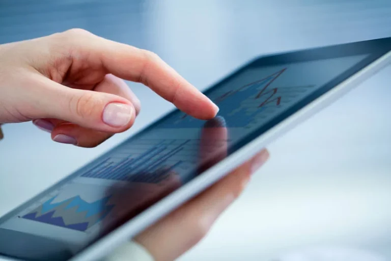 Touching tablet screen with graphs displayed.